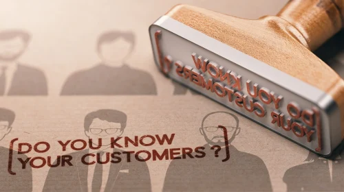 A rubber stamp marking the words “Do you know your customers?” onto paper, symbolizing the KYC onboarding process