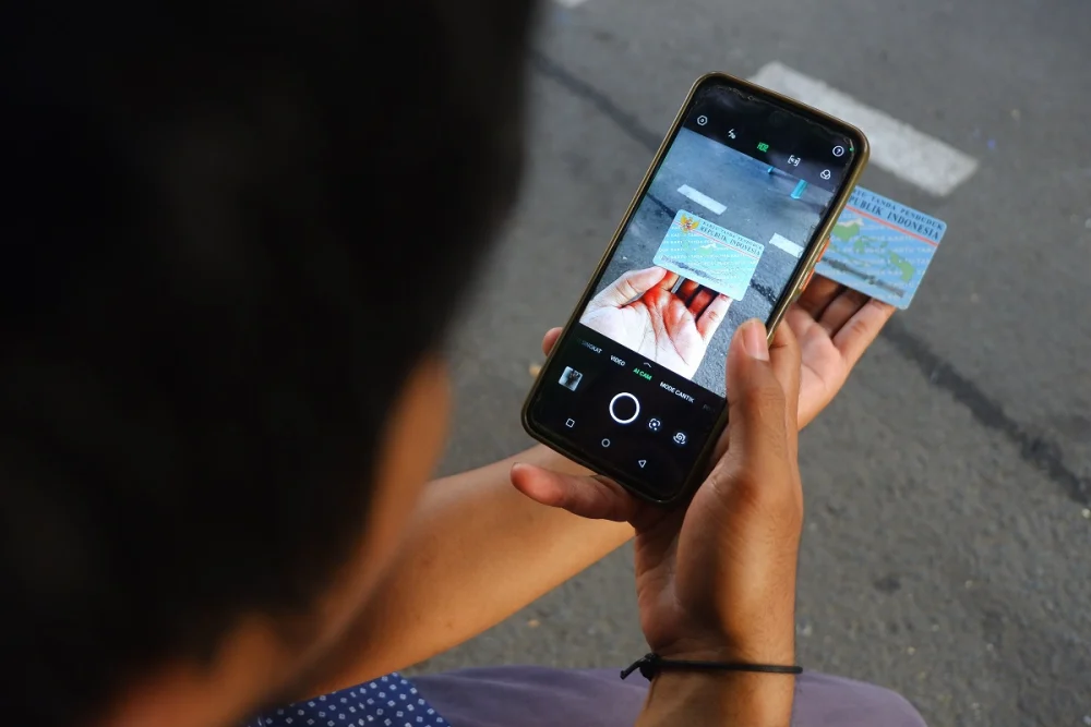 Person taking a photo of their ID card for digital KYC verification during bank onboarding