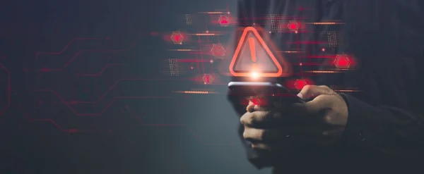 Conceptual image of a person holding a smartphone with digital warning symbols, representing corporate security trends in mobile threat detection and real-time alerting