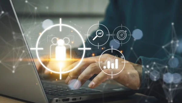 Hands typing on a laptop with digital targeting and analytics icons, representing difficulty identifying high-risk customers and detecting synthetic identities during KYC screening