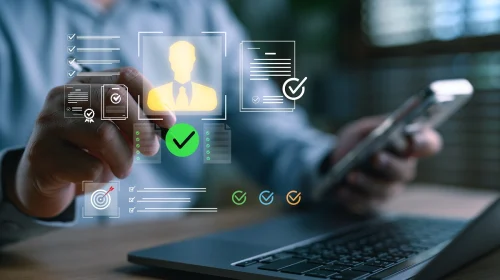 Businessperson using a laptop and smartphone with digital ID verification icons representing KYC and AML compliance